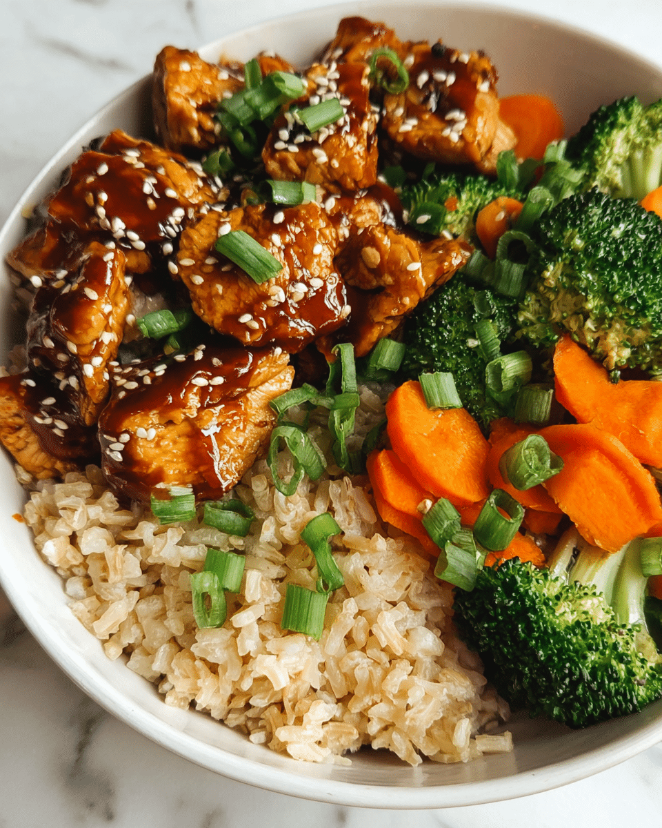 A white bowl holds a meal with three main parts. On the left side, there is a layer of light brown cooked rice with a soft, slightly sticky texture. On the upper left, pieces of glazed chicken with a shiny, dark brown sauce are placed on top of the rice; the chicken has a smooth texture and is sprinkled with small white sesame seeds. On the right side, vibrant green broccoli florets and bright orange carrot slices form a fresh vegetable mix. Some chopped green onions are scattered on top of the chicken and vegetables. The bowl sits on a white marbled surface. Photo taken with an iphone --ar 4:5 --v 7